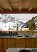 Kitchen in modern wooden house with view of wintry landscape