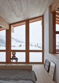 Bedroom in modern wooden house with view of wintry landscape