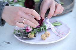 Hands arranging posy with ranunculus on vintage cutlery