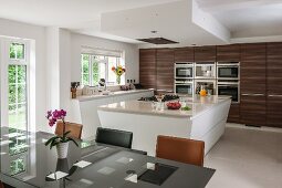 Island counter and dark wooden cupboards in modern kitchen-dining room