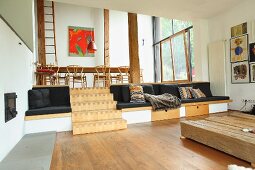 Split-Level Wohnbereich mit eingebauten Sitzmöbeln und Holztreppe