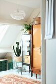 Various retro furnishings and house plants below sloping ceiling