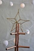 Golden wire star on Christmas tree made from copper piping