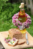 Flasche mit Kleeblütenkranz dekoriert und mit Brot auf Holzbrett