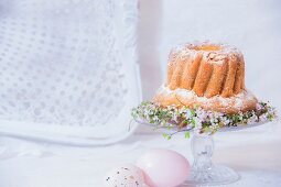 Bundt cake on decorated cake stand next to Easter eggs