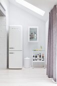 Retro fridge next to drinks trolley in white kitchen