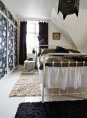 White metal bed in black and white attic bedroom