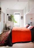Rote Tagesdecke auf einem mit Wandschränken umbautem Bett
