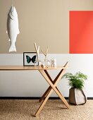Ornaments on designer table, fish sculpture hung on wall and accent of colour on wall