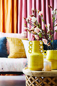 Yellow vases with branches of magnolia on the coffee table