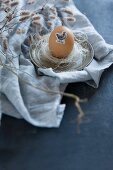 Osterei mit Tiermotiv beklebt auf Zinnteller