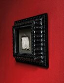 Elegant silver mesh purse in black picture frame on red wall