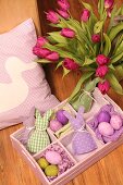 Vase of tulips and pastel Easter ornaments in wooden tray