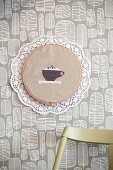 Hand-made wall decoration: coffee cup embroidered on cloth with lace trim and paper doily
