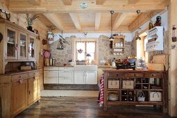 Offene Küche mit Anrichte, Küchenblock und teilweise Natursteinwand in einer Holzhütte