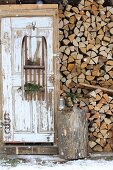 Axe and pine branches on old wooden sledge mounted on rustic wooden door and used as shelves