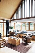 Cozy, high living area with leather armchairs and wooden chest in front of glazed gable wall