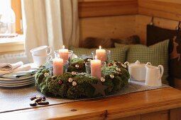 Moss Advent wreath with Christmas baubles and candles in glass jars