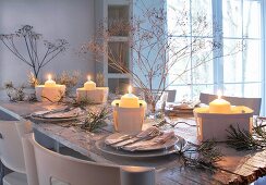 Wintry, romantic dinner table decorated with lit candles in chip wood baskets