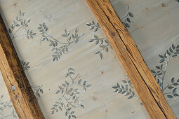 Wooden ceiling painted with pattern of leaves between beams