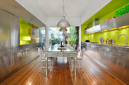 Mirrored table in kitchen with stainless steel cabinets and bright green wall