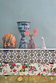 Collection of ornaments on top of chest of drawers with drawers covered in various patterns