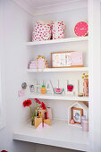 White built-in shelves with girl accessories above built-in desk