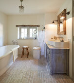 Washstand with countertop sink and free-standing bathtub in rustic bathroom