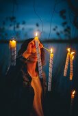 Frau entzündet aufgehängte Kerzen im Freien