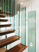 Stair treads with separate glass balustrade panels in front of several spherical pendant lamps