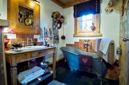 Free-standing zinc bathtub and washstand in rustic bathroom with traditional ambiance