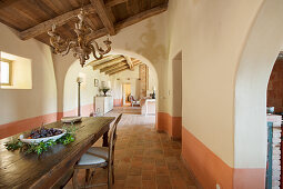 Long wooden table in dining room with arched doorways