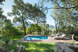 Pool mit Holzeinfassung und Liegen in mediterranem Garten