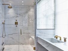 Glamorous modern bathroom with marble and gilt elements and glass doors