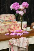 Romantisches Stillleben mit Pfingstrosenstrauß und dekorativen Pappschachteln