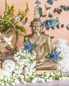 Buddha figurine decorated with white flowers and Eryngium flowers