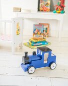 Blue toy train on white wooden floor in child's bedroom