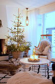 Kerzendeko auf dem Couchtisch vor dem Weihnachtsbaum im gemütlichen Wohnzimmer