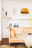 Bright leather couch with fur blanket and floor lamp in front of sideboard