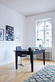 Dark desk and black leather chair in front of arched window