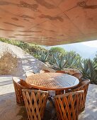 Concrete house projecting over round table on terrace with panoramic view