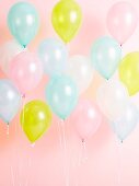 Pastellfarbene Luftballons als Partydekoration vor rosa Hintergrund