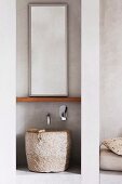 Waschbecken aus grob behauenem Stein unterm Spiegel