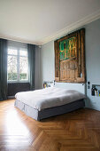 Old weathered wooden door on pale blue wall above bed