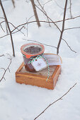 Einmachglas mit gebasteltem Etikett und eine Holzkiste im Schnee