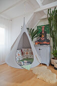Hanging chair in cosy reading area in front of picture of Frida Kahlo