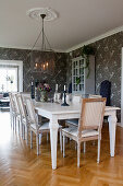 Gustavian-style table and chairs in dining room with grey floral wallpaper