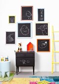 Children's drawings on blackboards with colourful frames on white wall