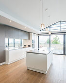 Open-plan kitchen island under open ceiling with glazed gable-end wall