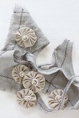 Small fabric rosettes with beads on piece of frayed fabric